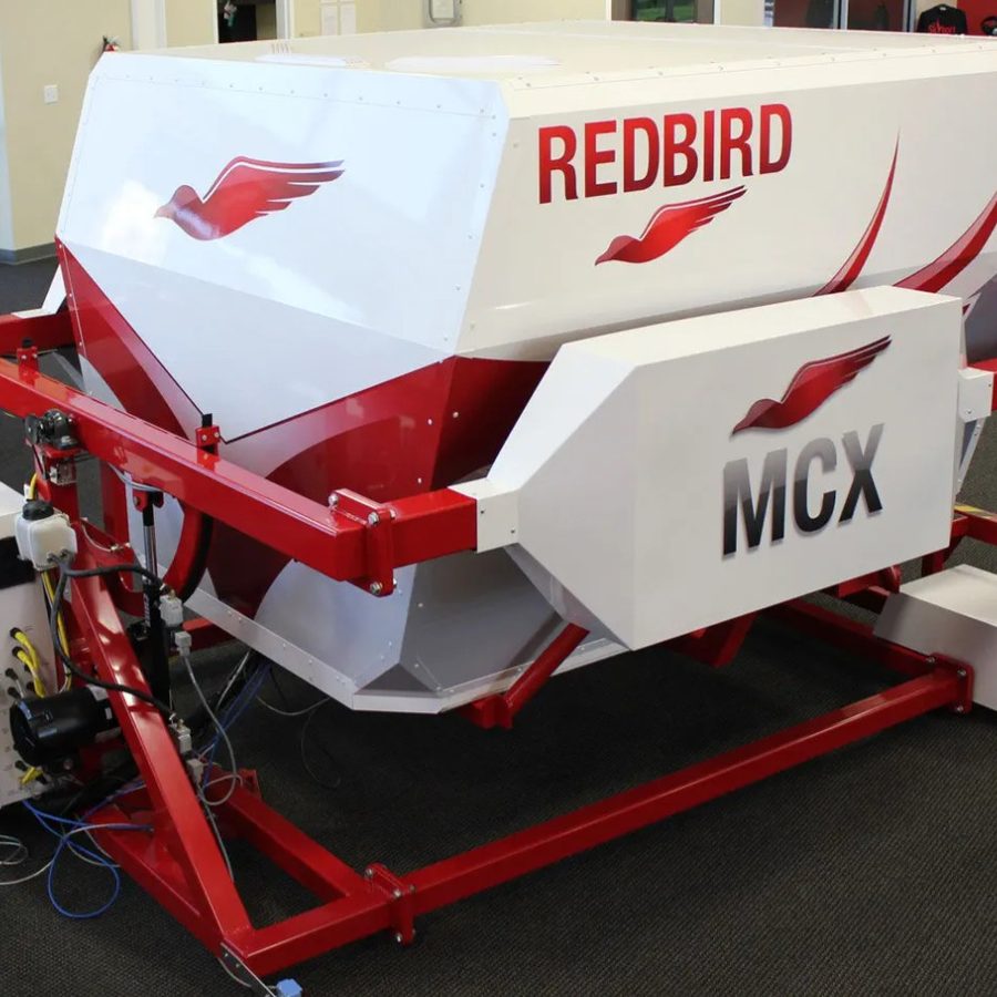 The Redbird MCX cockpit mounted on its red full-motion actuator frame