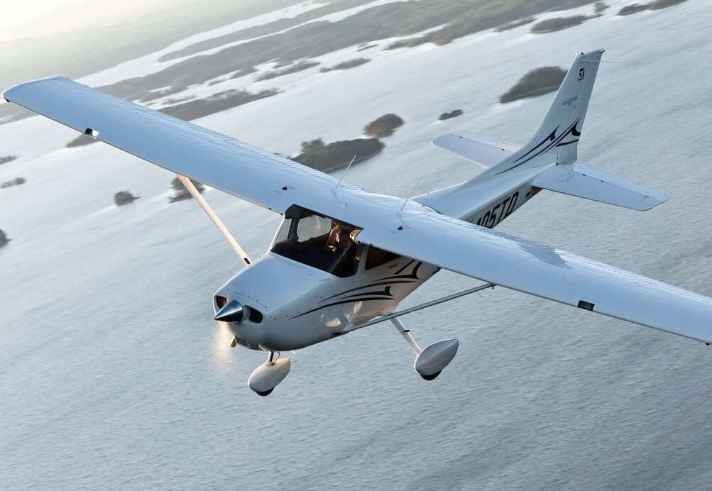 A Cessna 172 in flight above a coastline