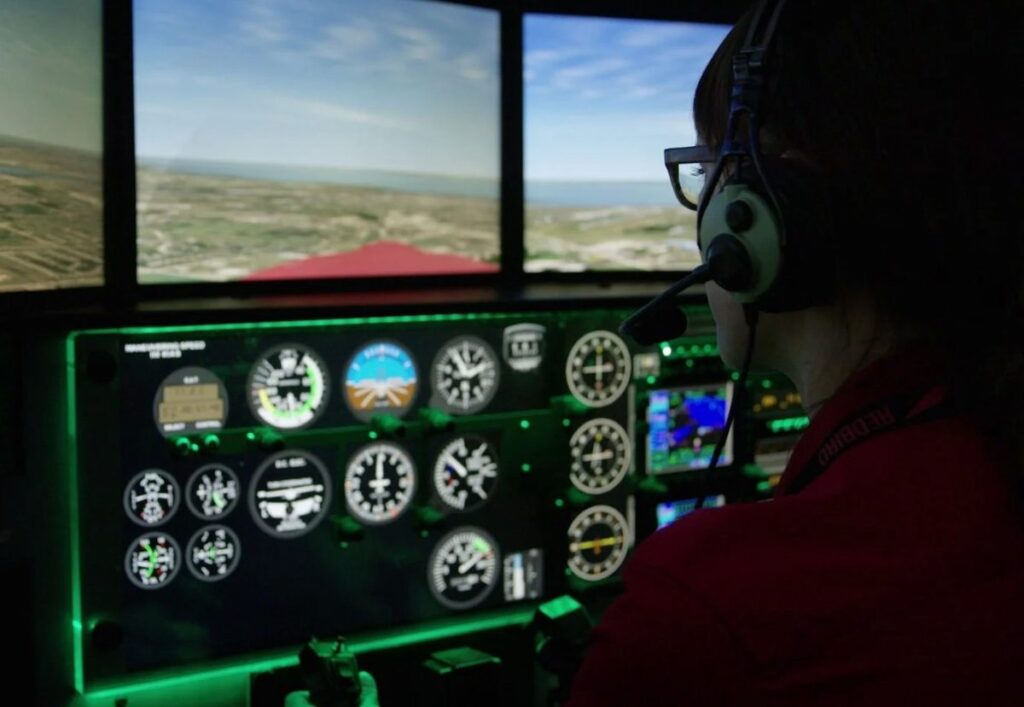 A student in a headset flying the Redbird MCX simulator