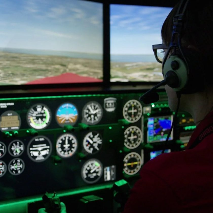 A pilot in a headset flying the simulator from the left seat